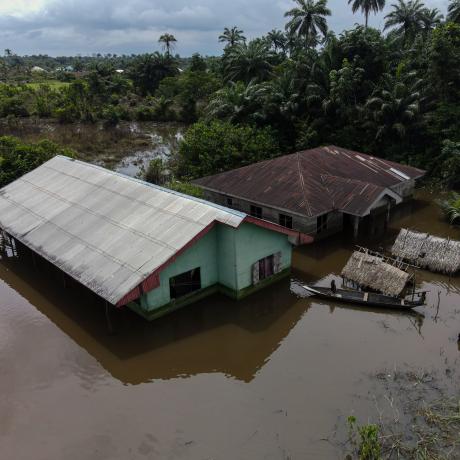 Children use a boat to navigate around their flooded community.